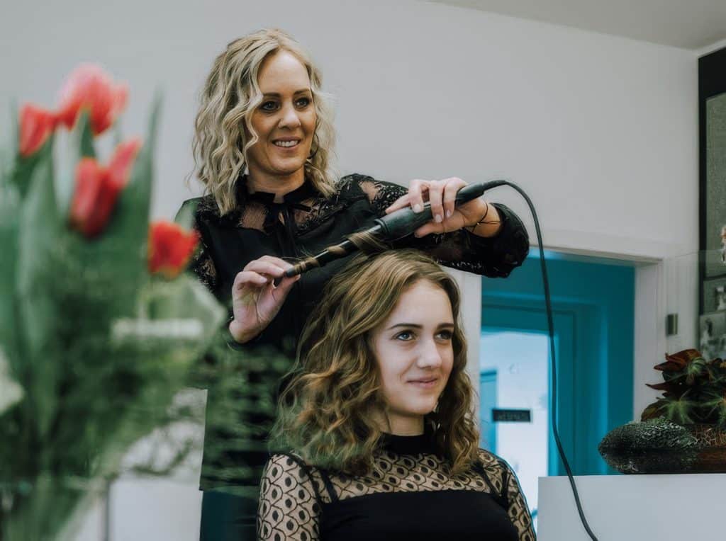 Simone macht mit dem Lockenstab gerade Locken bei einer junden Dame
